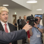Jo johnson wearing a suit and tie holding a cell phone.