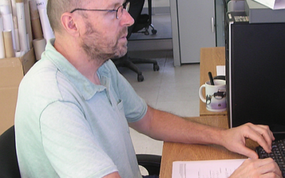 A man sitting at a table using a laptop.