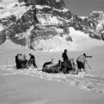 A group of people riding on the back of a horse in the snow.